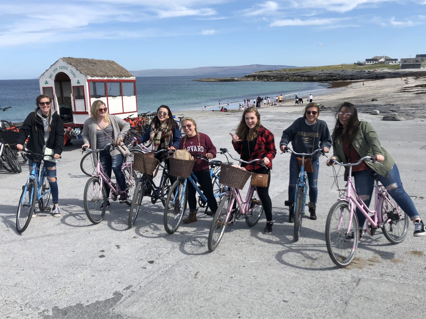 Girls posing on bikes in front of beach.