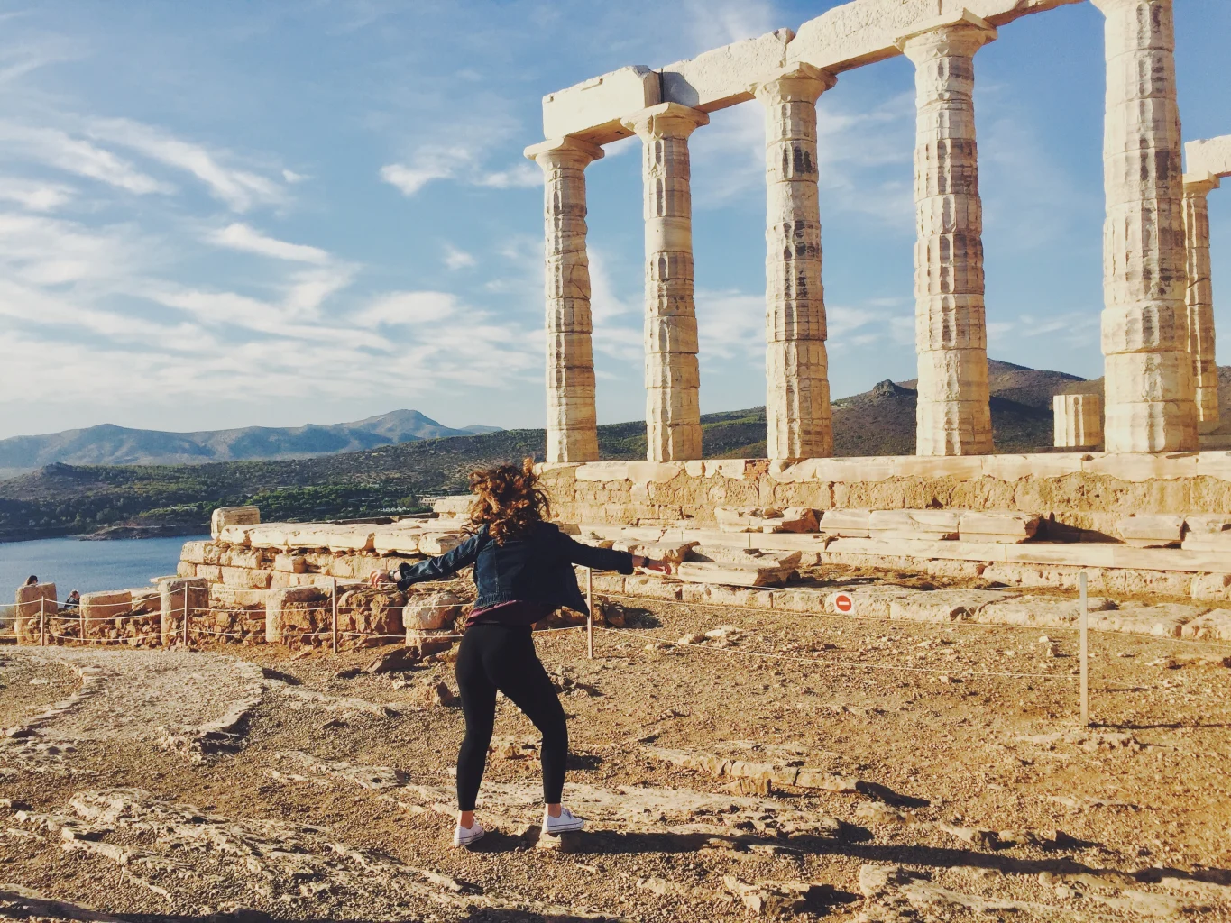 A student dancing near pillars on the Acropolis in Greece.