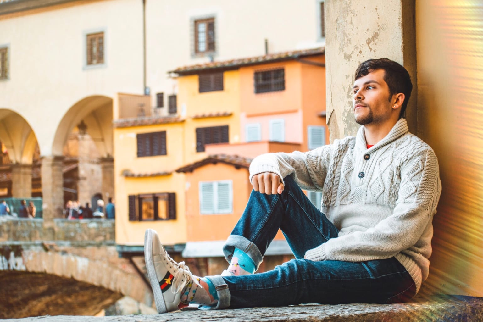 A student sitting on a ledge of a building in Italy.