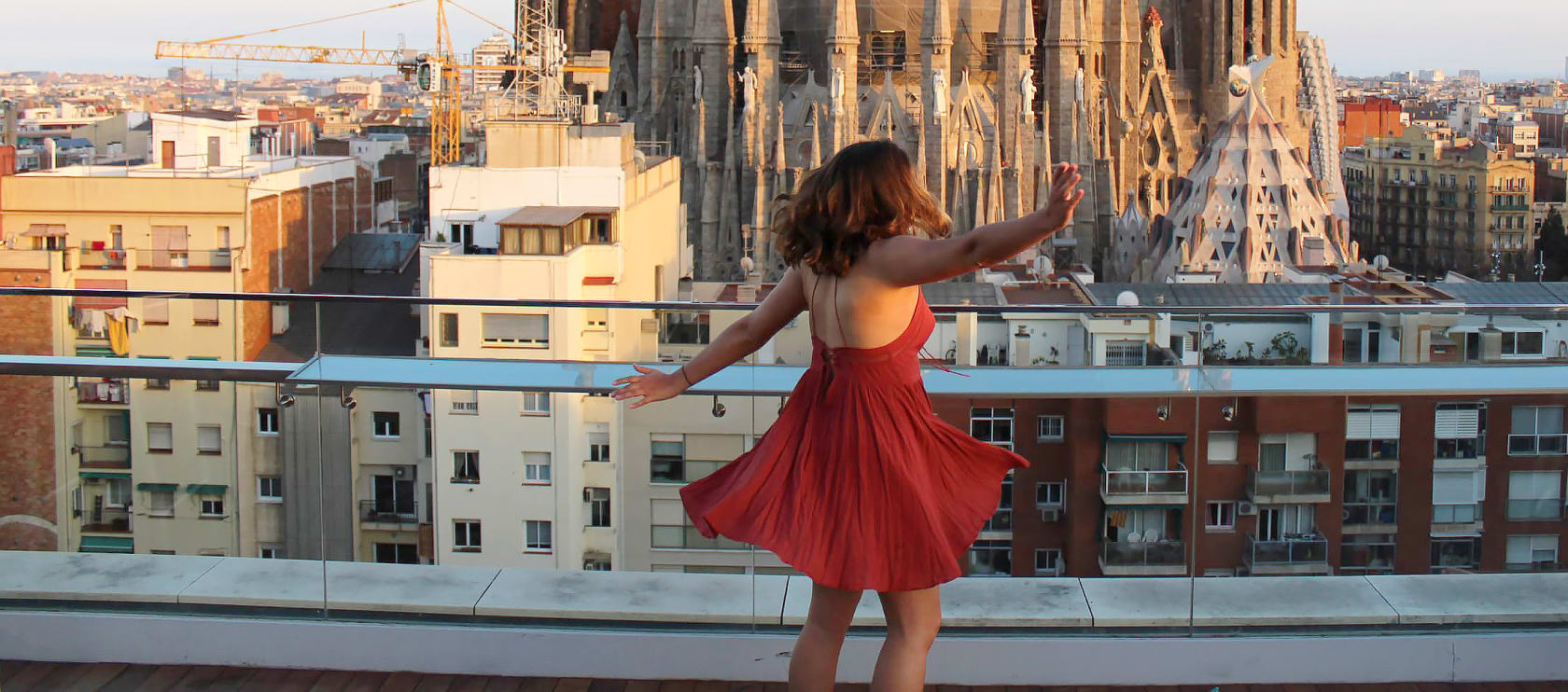 Girl in red dress dancing in front of building.