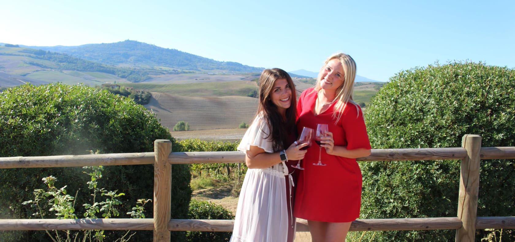 Two girls smiling holding wine.