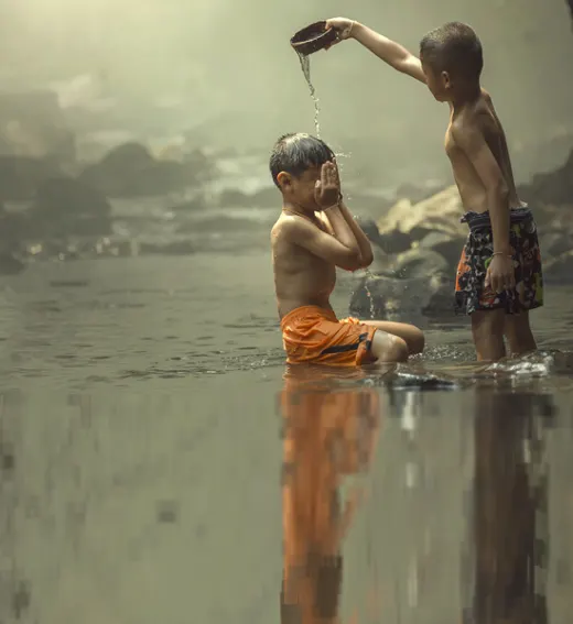 Two children washing up beside a river.