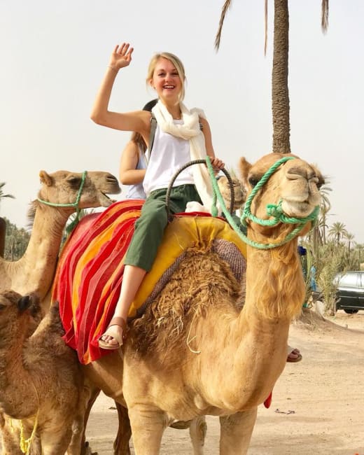 Girl on camel waving.