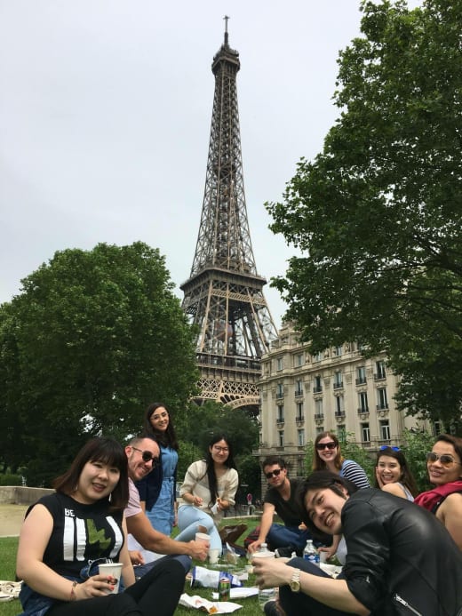 A group of students having a picnic in front of the Eiffel Tower.
