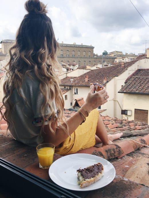 A student having breakfast outside on a veranda overlooking Florence, Italy.
