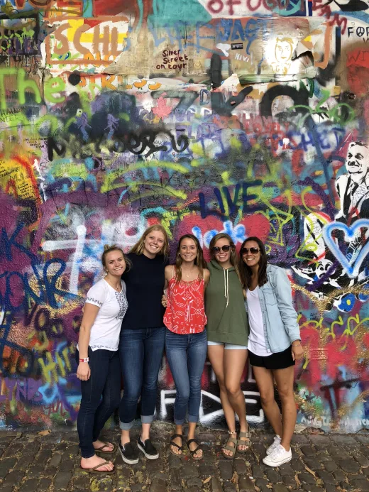 A group of students in front of a wall of graffiti.
