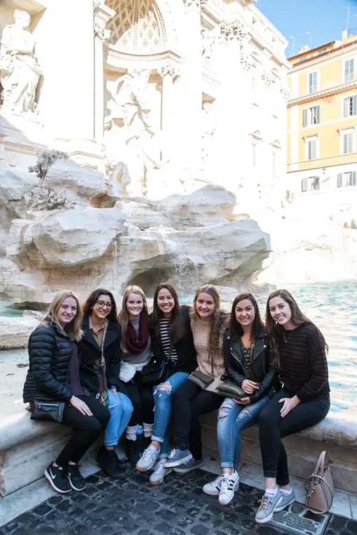 A group of students sitting in front of the Trevi fountain.