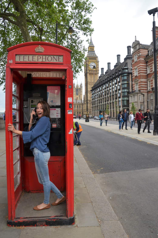 A student standing inside a red phone booth in London, England.