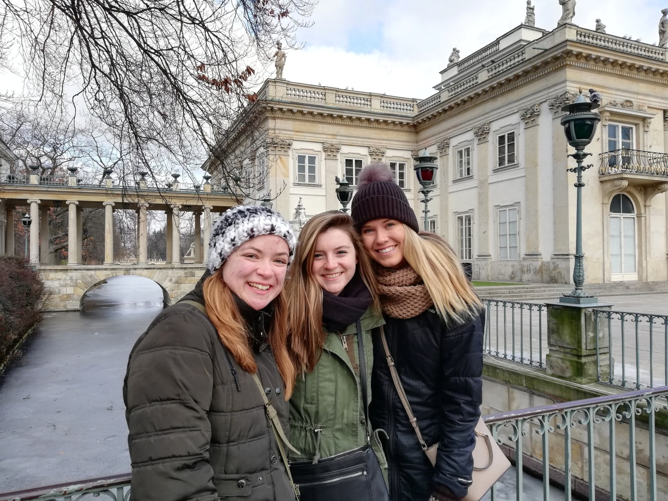 Three girls smiling in front of building.