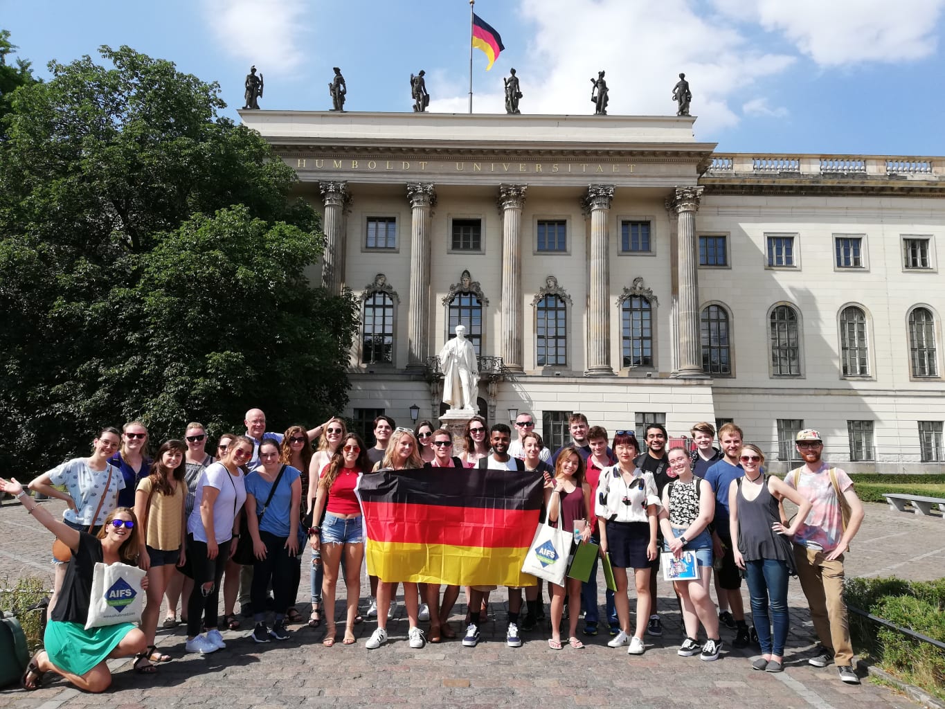 A group of students holding a German flag in front of Humboldt University.