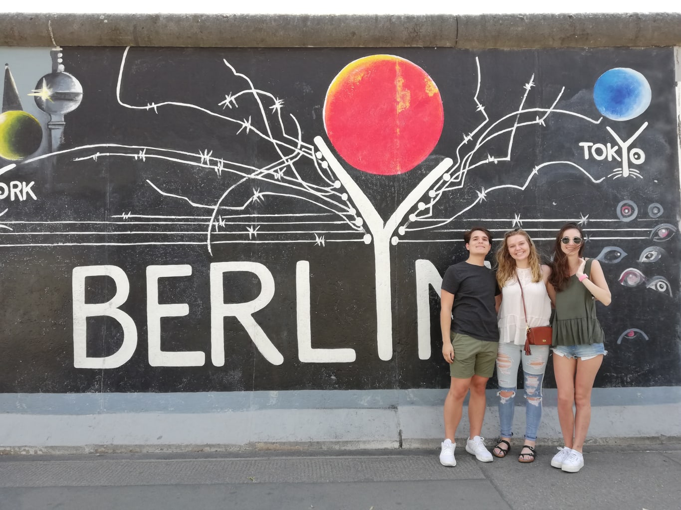 Three students in front of a mural in Berlin.