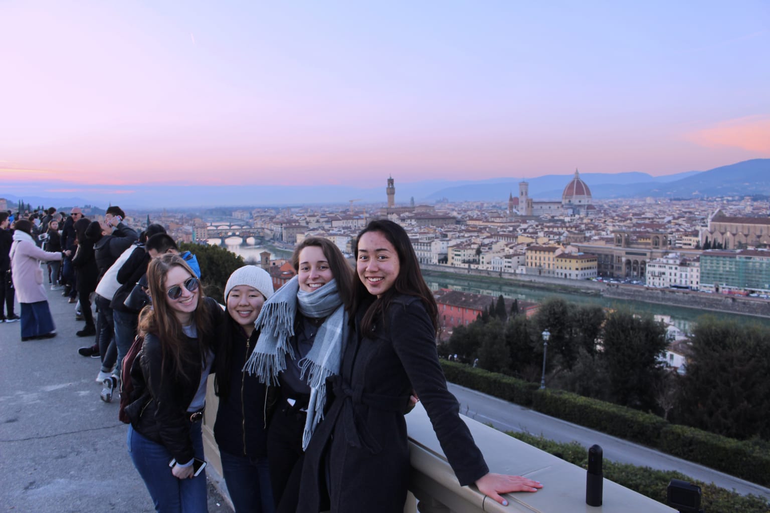 A group of students with a sunset in the background in Italy.