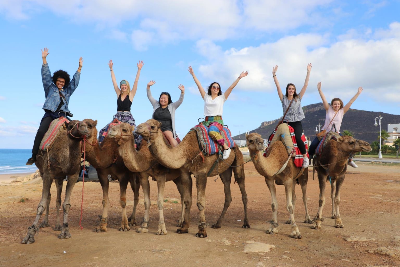 People on camels with their arms in the air.