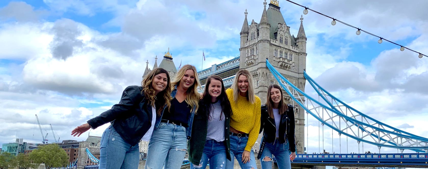 A group of students posing in front of the Tower Bridge in London.