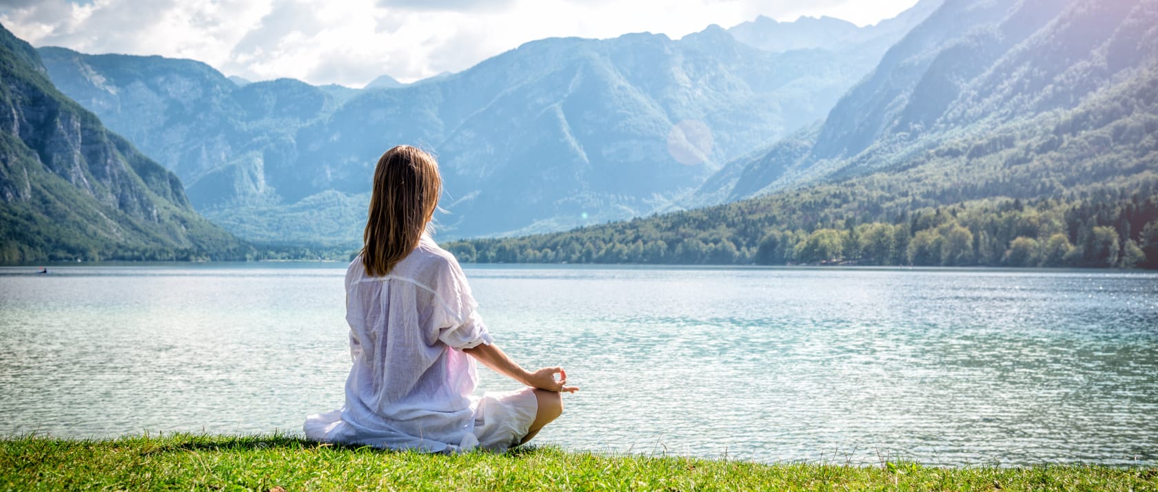 Young woman meditating by a lake.