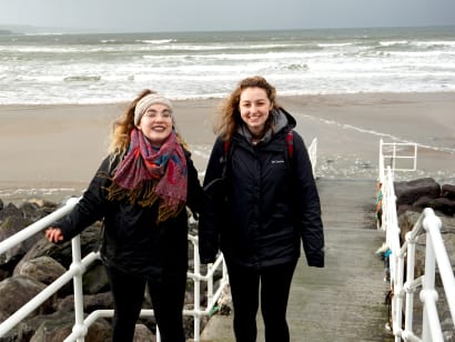 Two students walking on a beach in Limerick, Ireland.