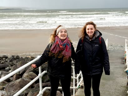 Two students walking on a beach in Limerick, Ireland.