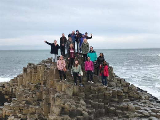 A group of students standing on a cliff alongside the ocean in Ireland.