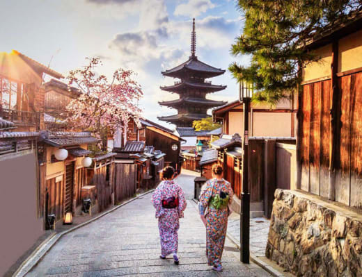 Two women wearing kimonos, walking through a street in Kyoto, Japan.