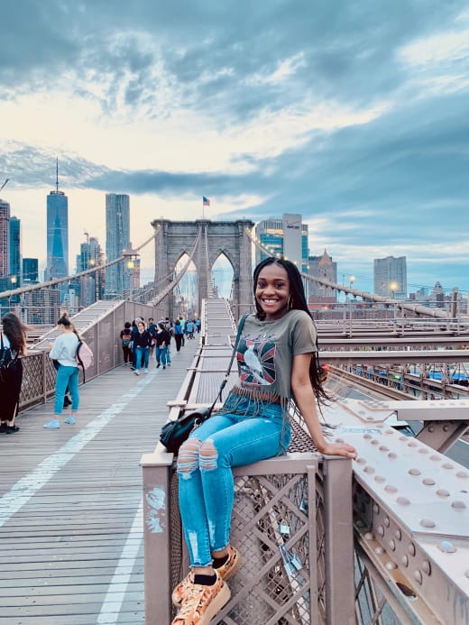 A student sitting on a ledge on the Brooklyn Bridge.