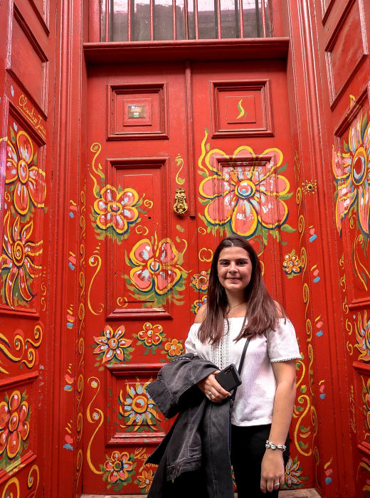 A student standing outside a read door with floral patterns.