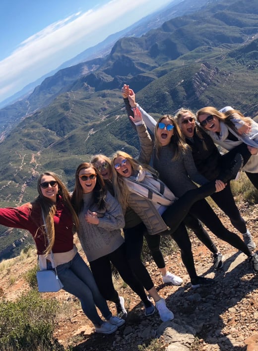 A group of happy students with a view of a mountain landscape in Spain.