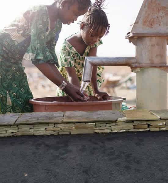 Two children washing their hands.