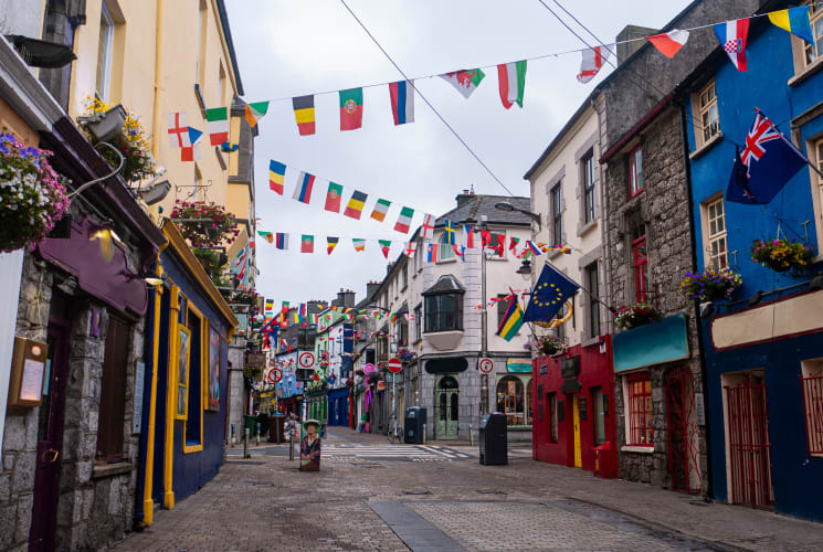 A street in Galway, Ireland with colorful buildings and flags.