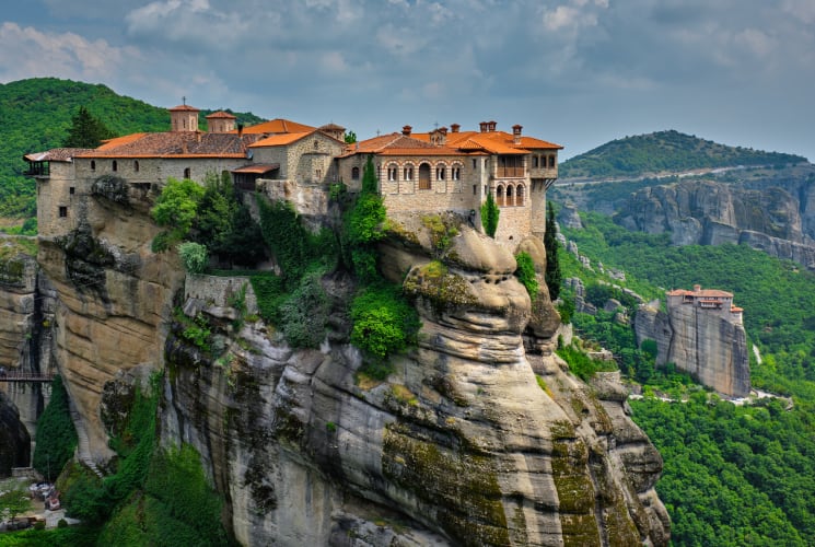 Buildings with orange roofs on a cliff in Meteora, Greece.