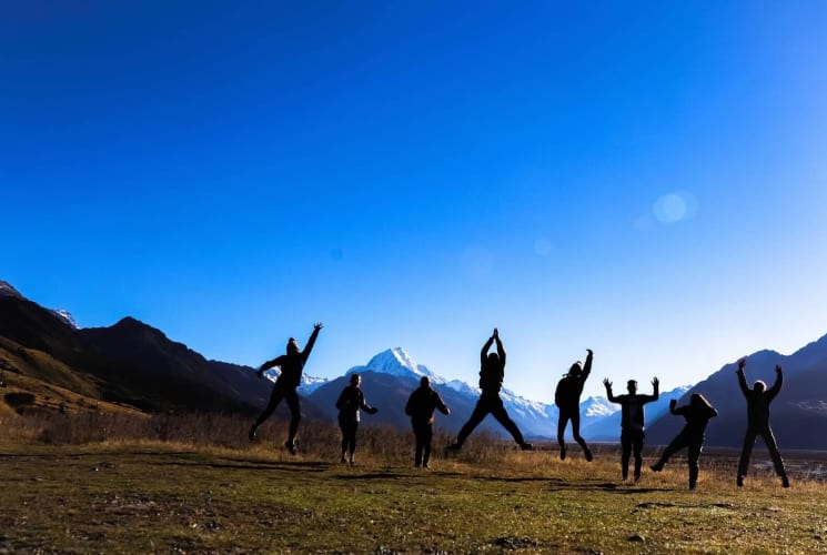 A group of students jumping in front of a mountain view in New Zealand.