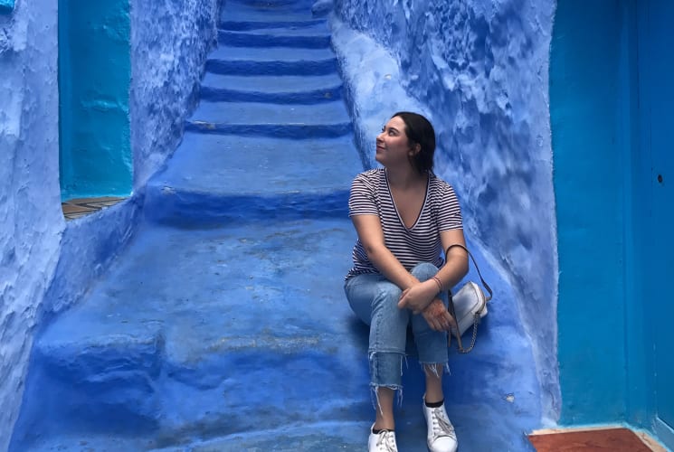 A student sitting on steps between blue buildings in Granada, Spain.