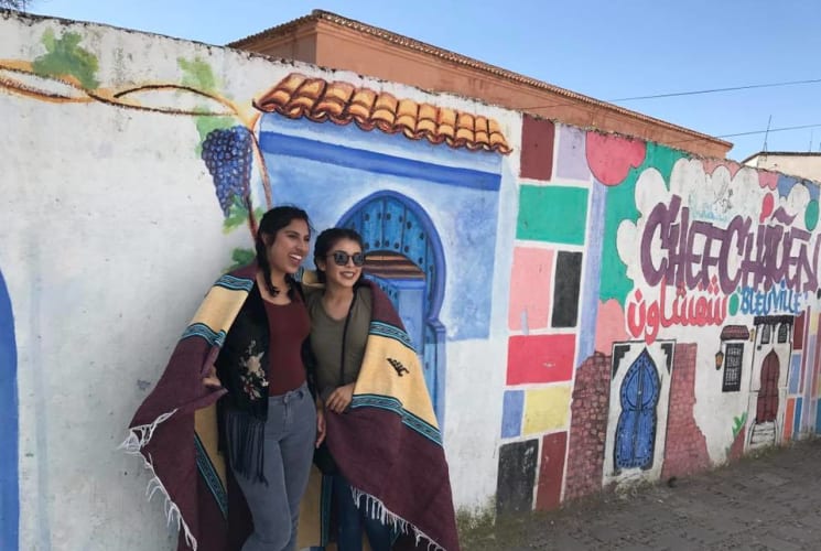 Two students standing in front of a colorful wall.
