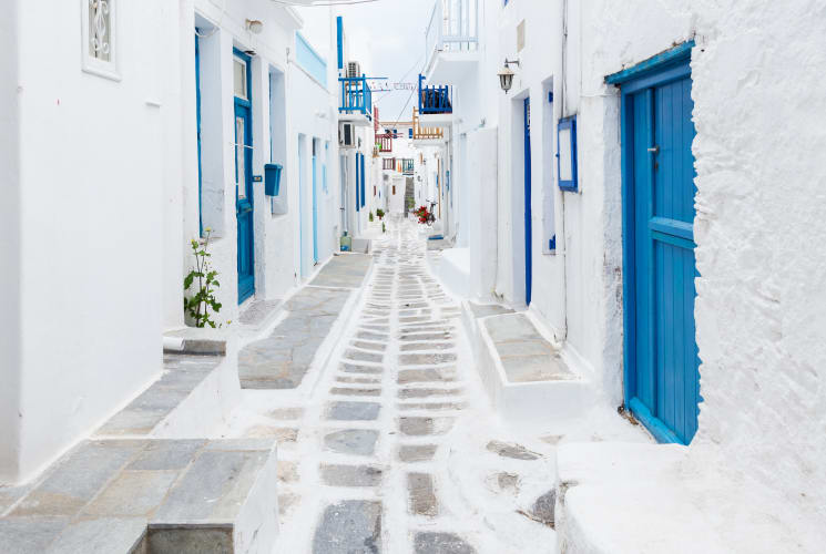 A street on a Greek Island with white buildings and blue doors.