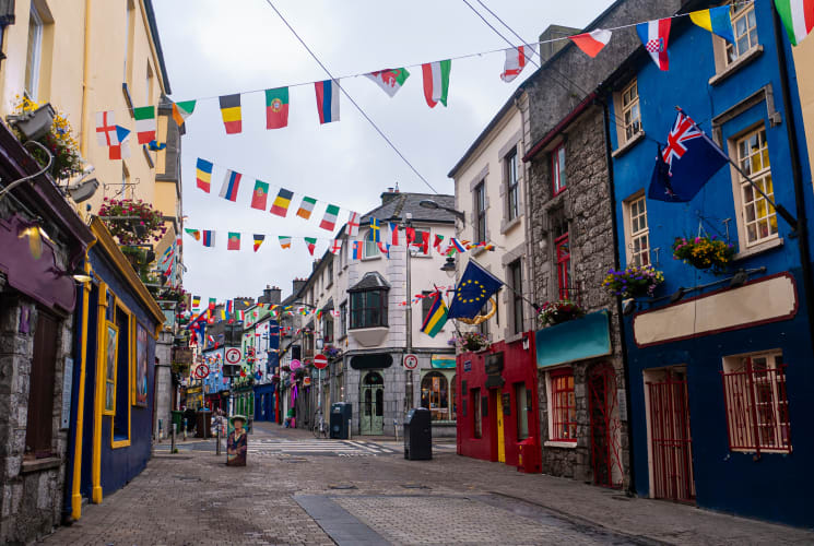 A street in Galway, Ireland with colorful buildings and flags.