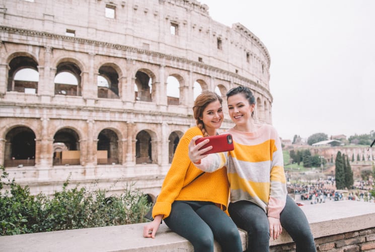 Two students taking a selfie in front of the Colosseum in Italy.