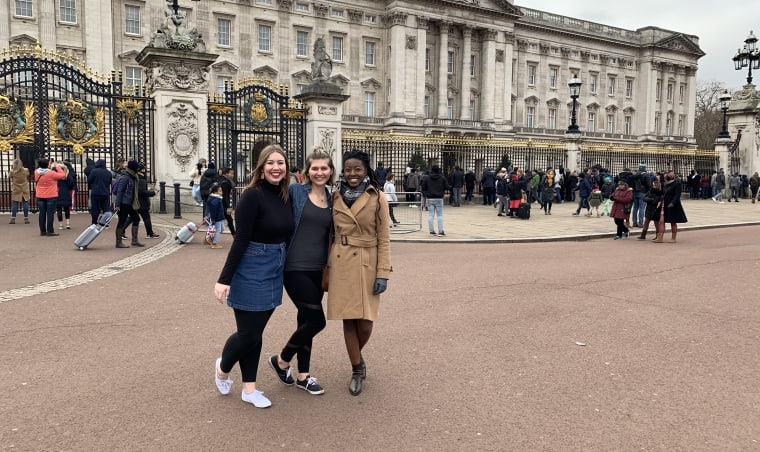 Three students in front of Buckingham Palace.