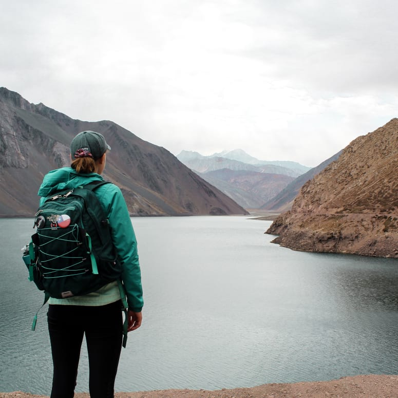 A student looking at a view of a lake between mountains.